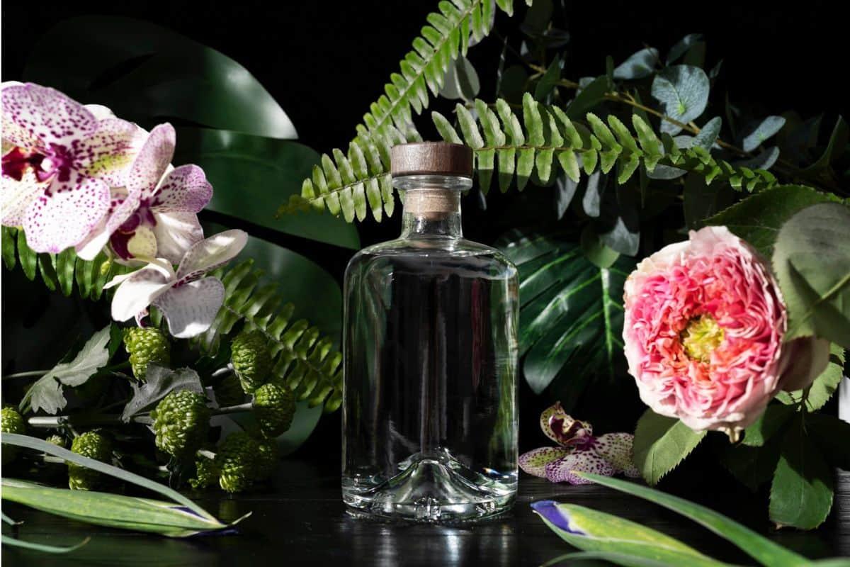 Botol parfum yang dikelilingi dedaunan dan bunga
