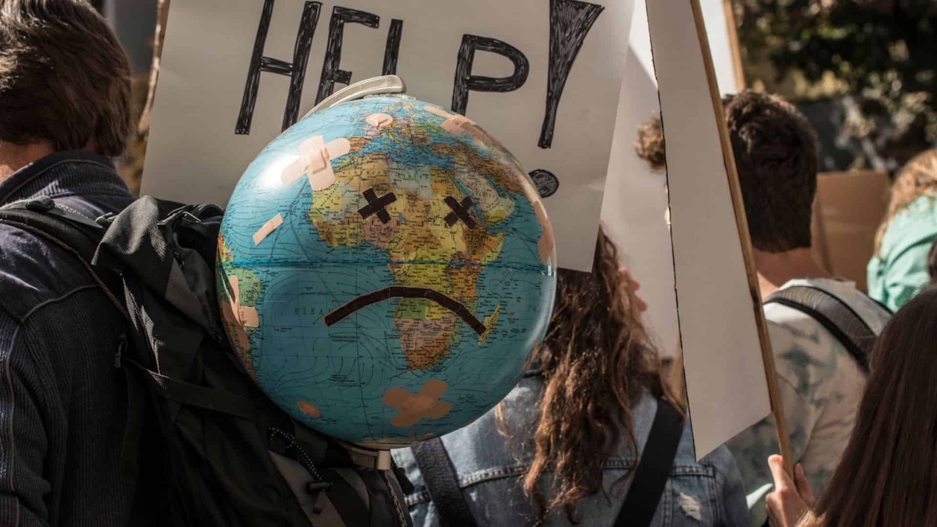 Foto orang sedang berdemo sambil membawa globe dengan ekspresi cemberut