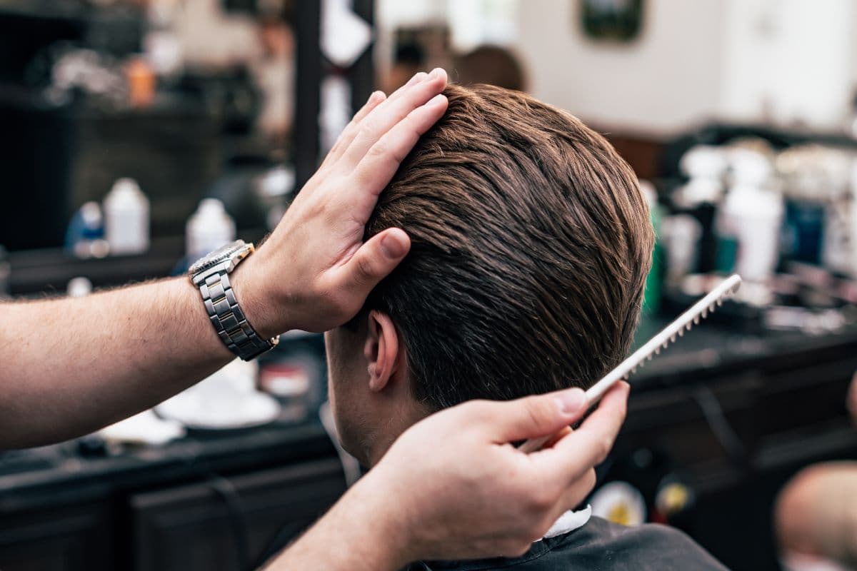 Seorang pria sedang dicukur rambutnya di barber shop