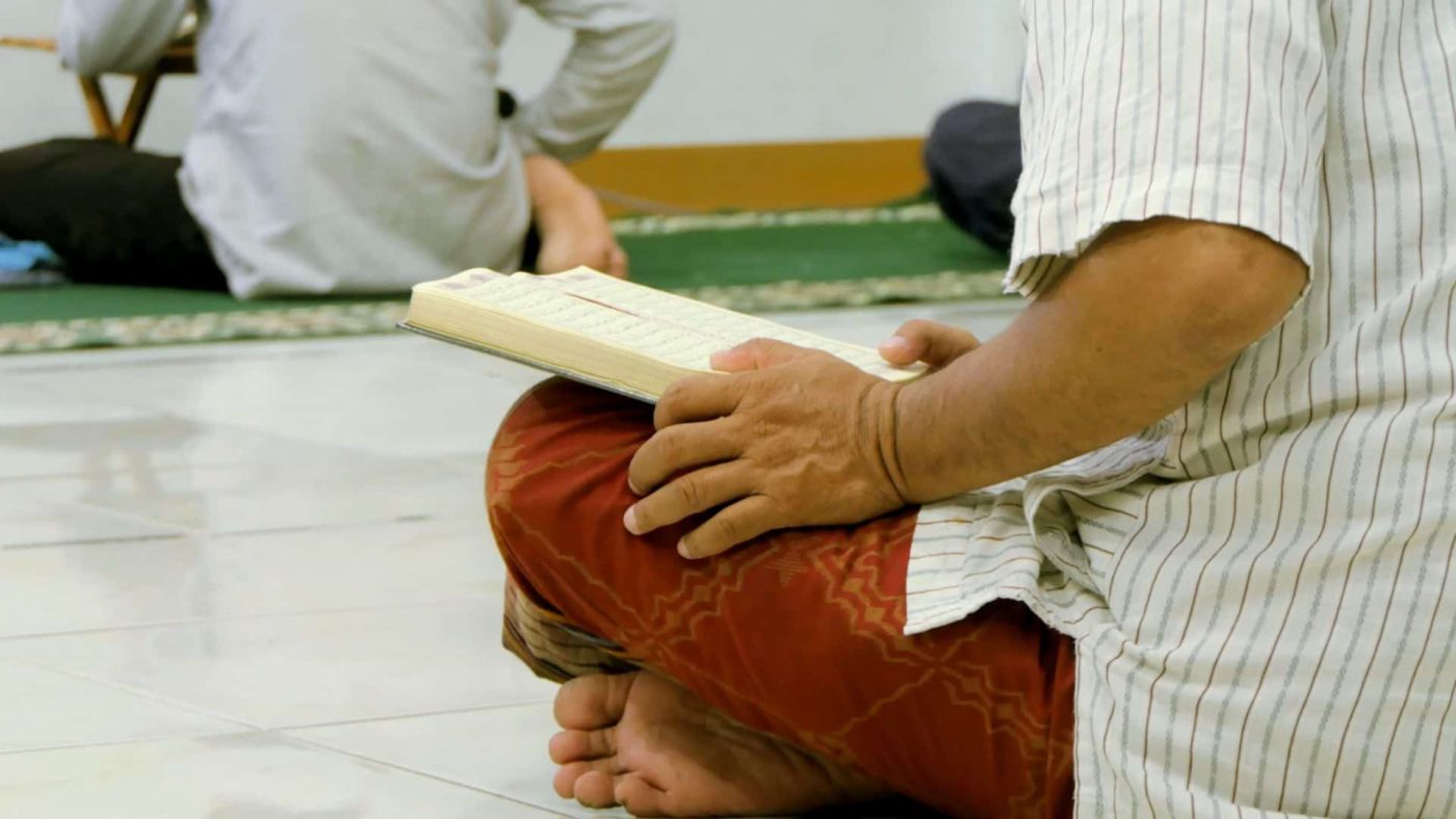 Seorang pria sedang membaca Al-Qur'an.
